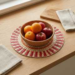 Étoile Flamboyante - Round placemat in handwoven seagrass, sun pattern – staged view – Handcrafted product, handmade · Kuênia
